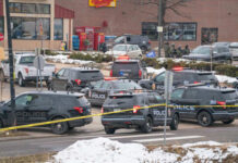 Multiple police vehicles at a scene with caution tape and emergency lights activated