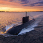 A submarine navigating through the ocean during sunset