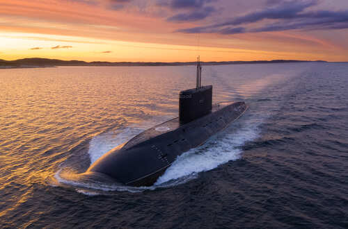 A submarine navigating through the ocean during sunset