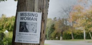 Missing person poster on a telephone pole with a woman's photo