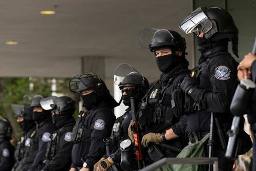 Group of law enforcement officers in riot gear standing in formation