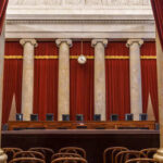 Interior view of a courtroom with red curtains and marble columns