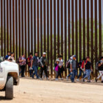Border Patrol vehicle near group of people walking