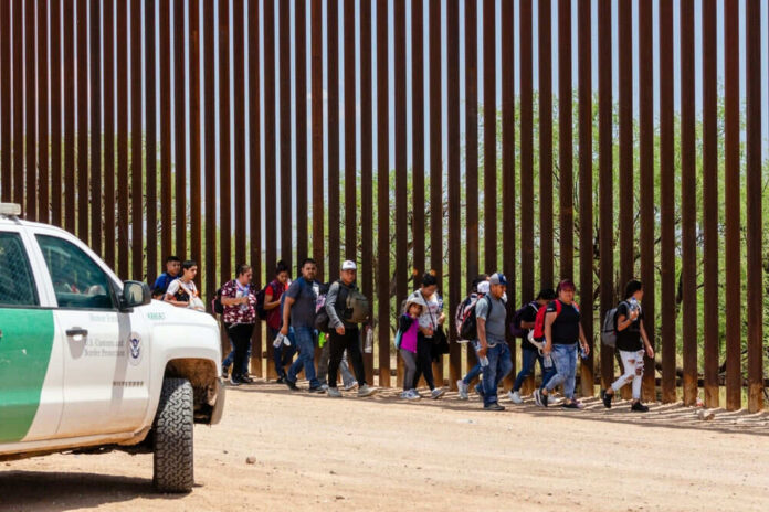 Border Patrol vehicle near group of people walking