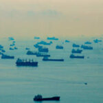 OIL CHOKEHOLD: Tehran Grabs The Wheel Numerous cargo ships scattered across a hazy ocean