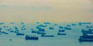 Numerous cargo ships scattered across a hazy ocean