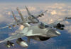 Two military fighter jets flying in formation above the clouds